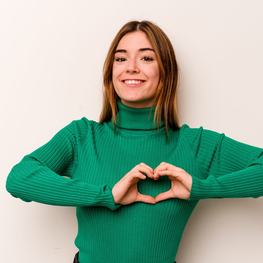 Joven mujer sonriente mostrando un corazón con las manos, simbolizando amor propio y autoestima